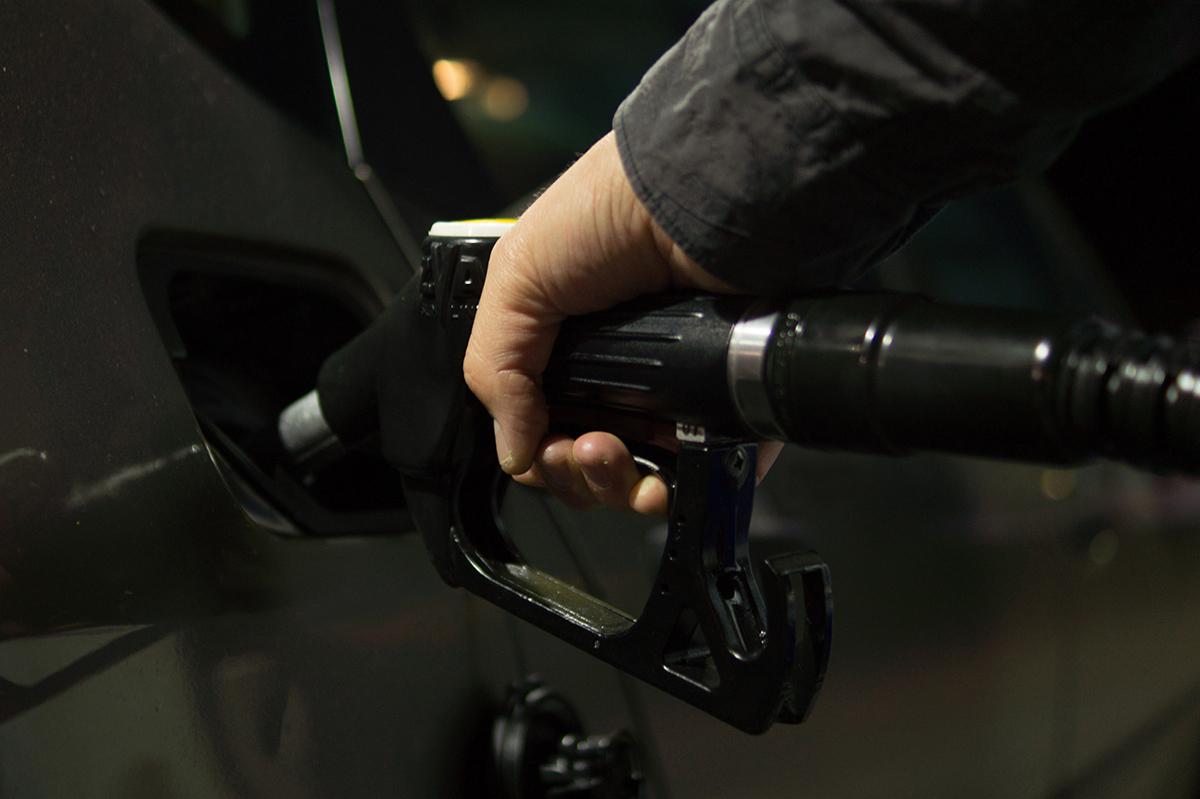 Person holding a gas pump nozzle to fill up a car tank