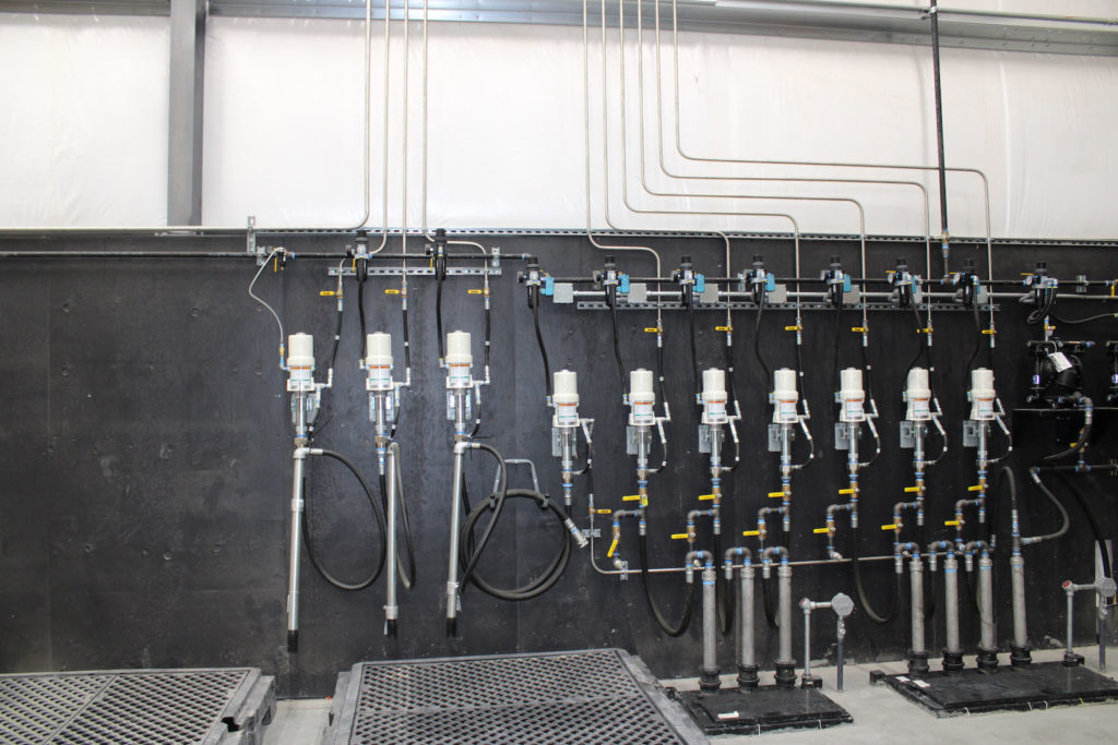 An industrial fueling system installation with an array of pipes, valves, and meters on a black wall, possibly part of a fuel distribution or monitoring system.
