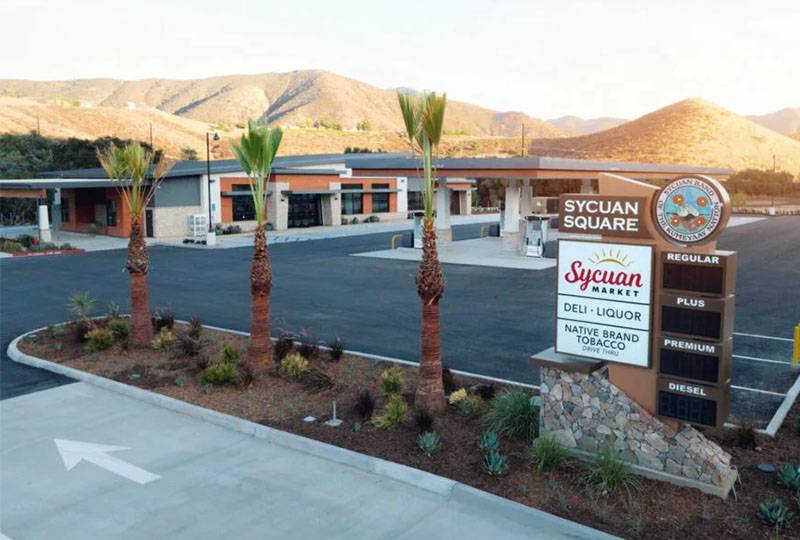 Sycuan Square fuel station and market with palm trees, located in a mountainous area.
