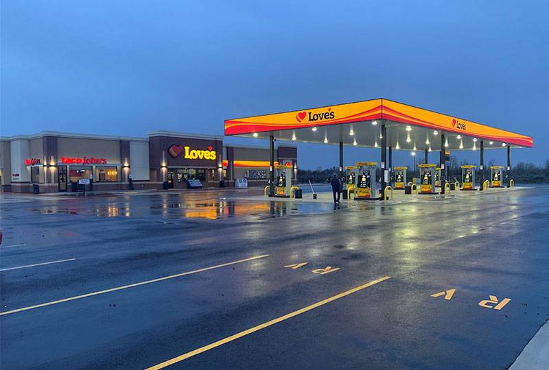 Love's Travel Stop and Taco John's location illuminated in the early evening, featuring multiple fuel pumps and a convenience store.